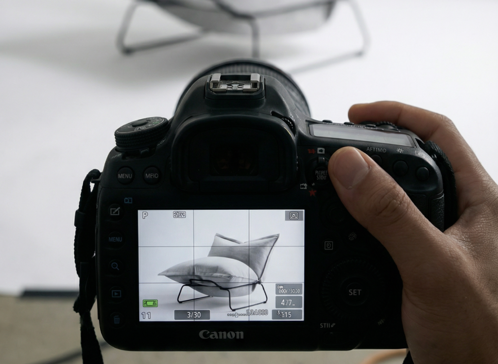 Photoshooting Eine Hand hält eine Kamera, die auf einen modernen Stuhl fokussiert ist.